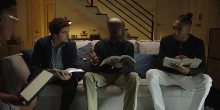 Three men reading Bibles together on a couch