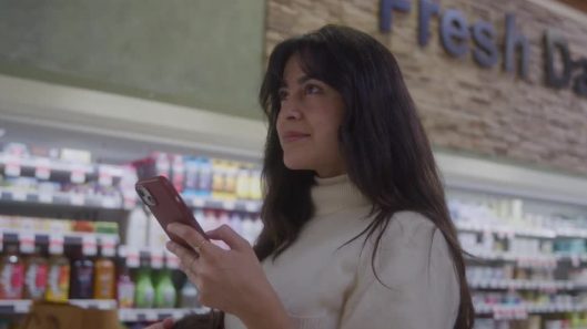 A woman checking her phone in a grocery store