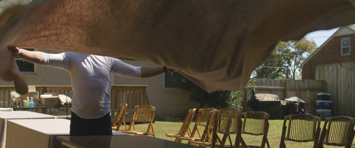 A tablecloth snapping open over a backyard table