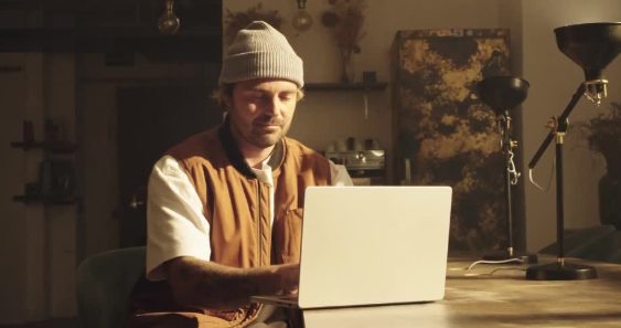 A man talking at a laptop in a warm room